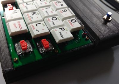 Atornillo el PCB del teclado a la caja. Y limpio los restos de plástico de las teclas rotas.